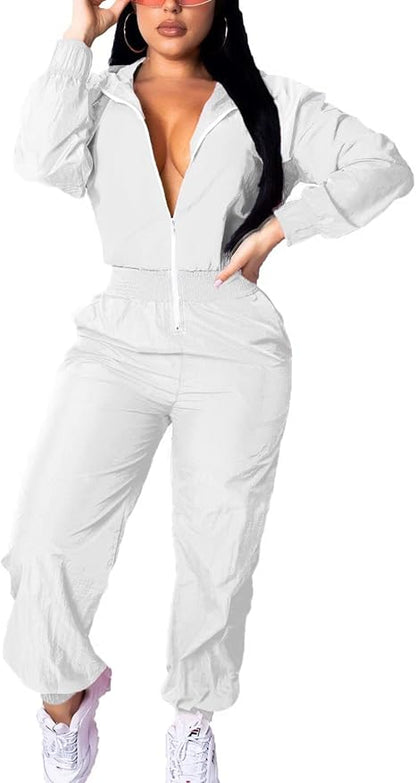 Frau in weißem Jumpsuit mit Reißverschluss und Kapuze, modisch, sportlich, elegant.