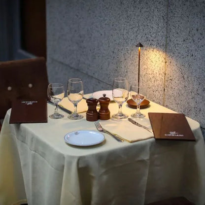 Eleganter Restauranttisch mit Weingläsern, Speisekarten und Tischlampe, ideal für romantisches Dinner.