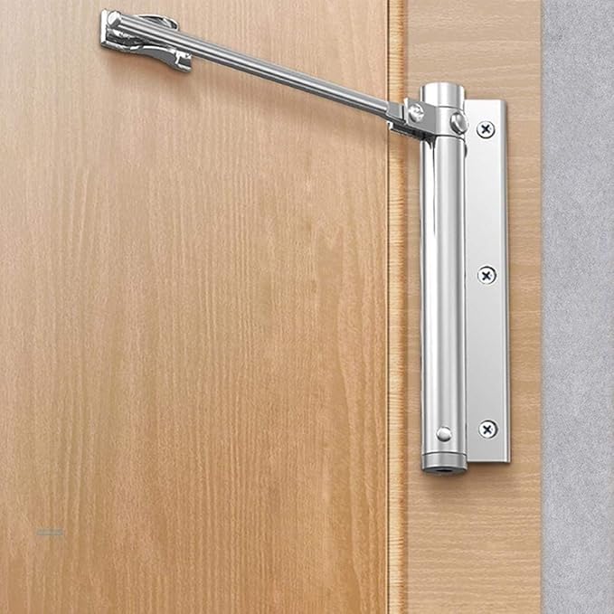 Silverfärgad dörrstängare med utfälld arm monterad på en ljus trädörr, sedd från sidan 2