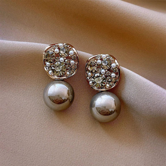 Elegante Ohrringe mit Perlen und Strasssteinen auf beigem Stoff, Schmuck, Accessoires.