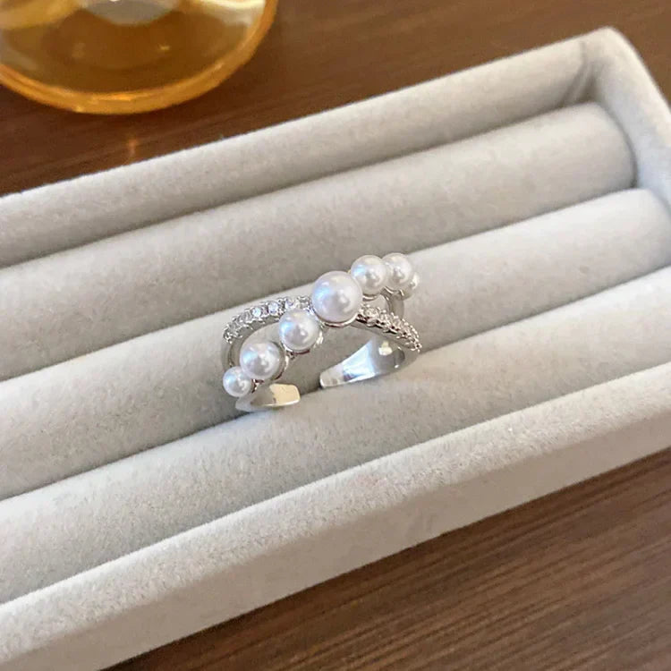 Silberner Ring mit Perlen und Strasssteinen auf Samtkissen, eleganter Schmuck, Damenaccessoire.