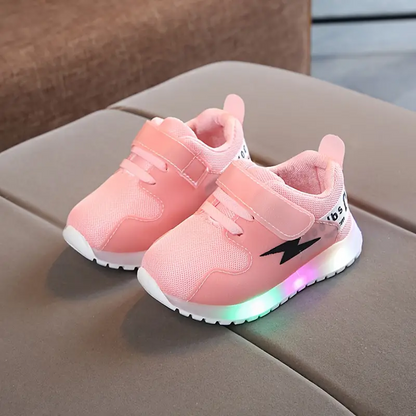 Rosa LED-Kinderschuhe mit Klettverschluss, Blitz-Design, auf grauem Sofa.