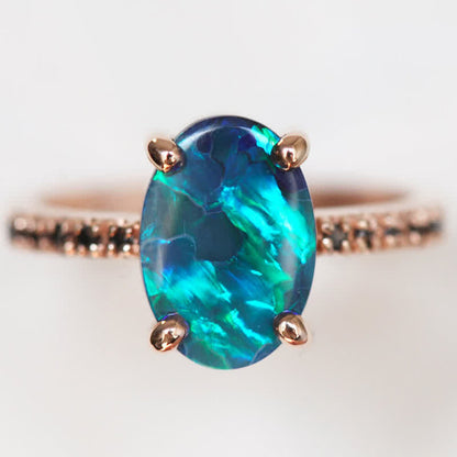 Opalring mit blau-grünem Edelstein, Roségoldfassung, elegantes Schmuckdesign.