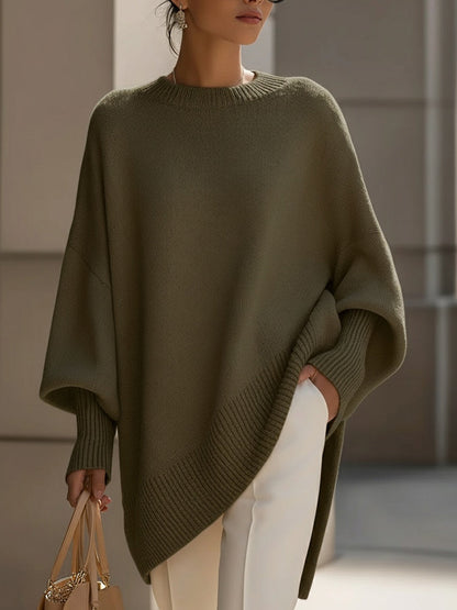 Modell i olivgrön stickad poncho med ribbad kant, vita byxor och handväska 8