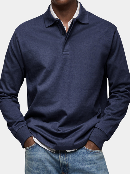 Närbild framifrån på marinblå långärmad pikétröja med knappgylf och ribbade muddar, bärs över randig skjorta med jeans. 1