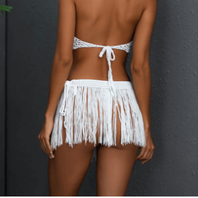 Frau in weißem Häkel-Bikini mit Fransen, Rückenansicht, Sommermode, Strandbekleidung.