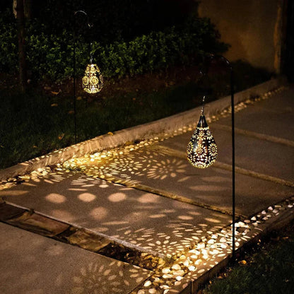 Solarbetriebene Gartenleuchte, tropfenförmig, schwarz-gold, beleuchtet Gehweg nachts.
