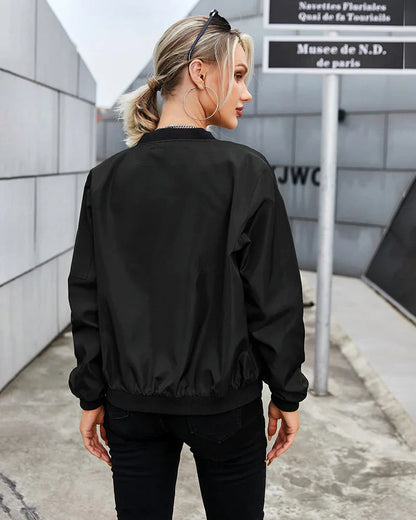 Frau in schwarzer Bomberjacke, Rückansicht, urbaner Hintergrund, modisch, lässiger Stil.