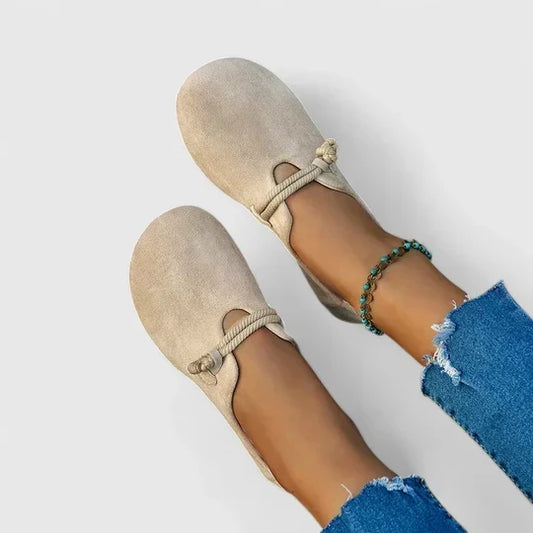 Beigea mockaloafers med snodd över vristen, sedda uppifrån på fötter i jeans och fotkedja 1