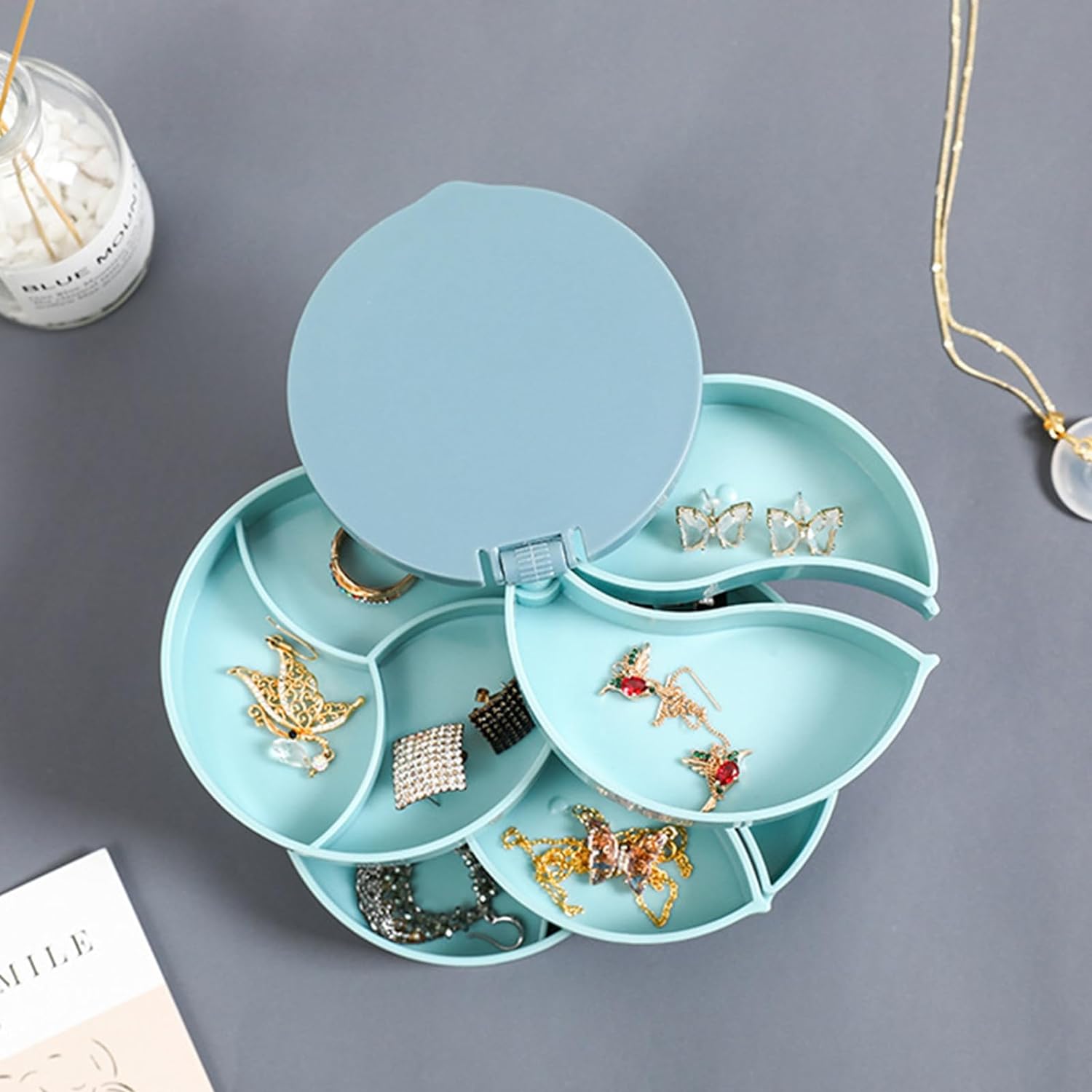 Blauer Schmuck-Organizer aus Kunststoff, drehbar, mit mehreren Fächern für Ohrringe und Ringe.