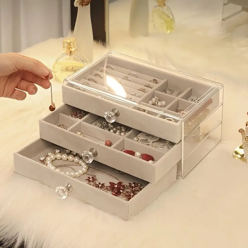 Transparente Schmuckbox mit Schubladen, beige, zur Aufbewahrung von Ohrringen und Halsketten.
