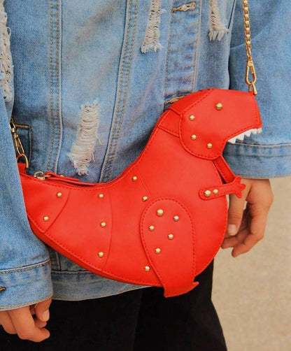 Rote Dinosaurier-Umhängetasche aus Leder mit Nieten, getragen über zerrissener Jeansjacke.