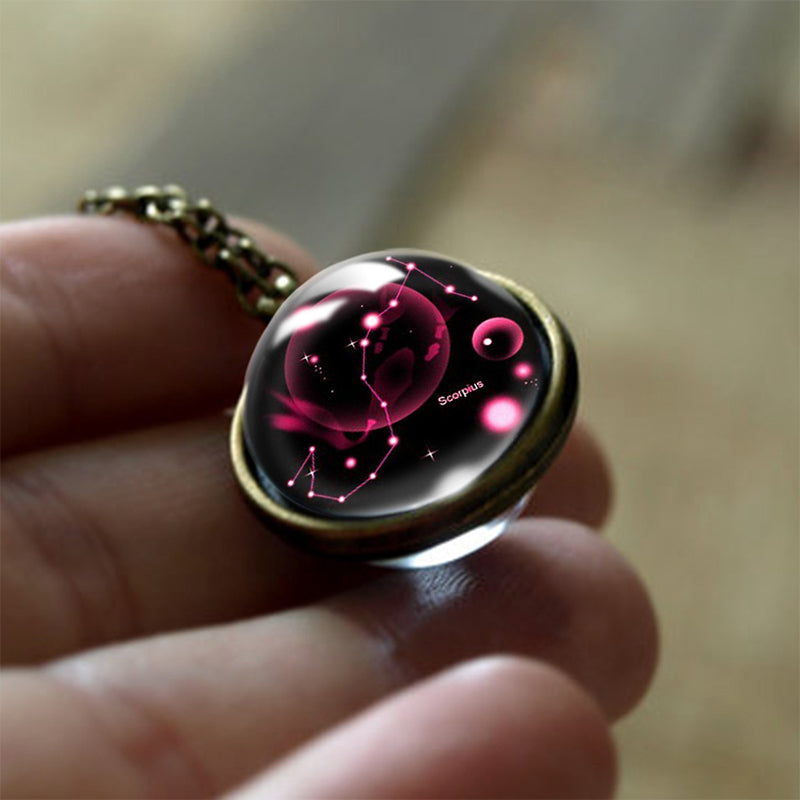 Glasanhänger mit Sternbild Skorpion, rosa Leuchten, bronzefarbene Fassung, Astrologie-Schmuck.