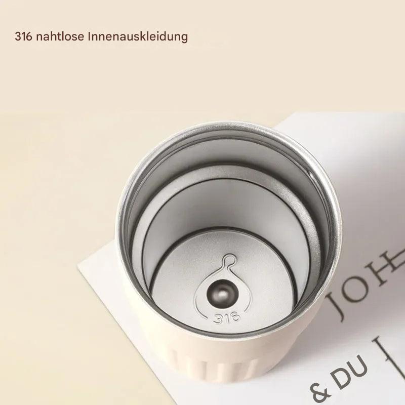 Weißer Thermobecher aus Edelstahl 316, nahtlose Innenauskleidung, auf Buch liegend.
