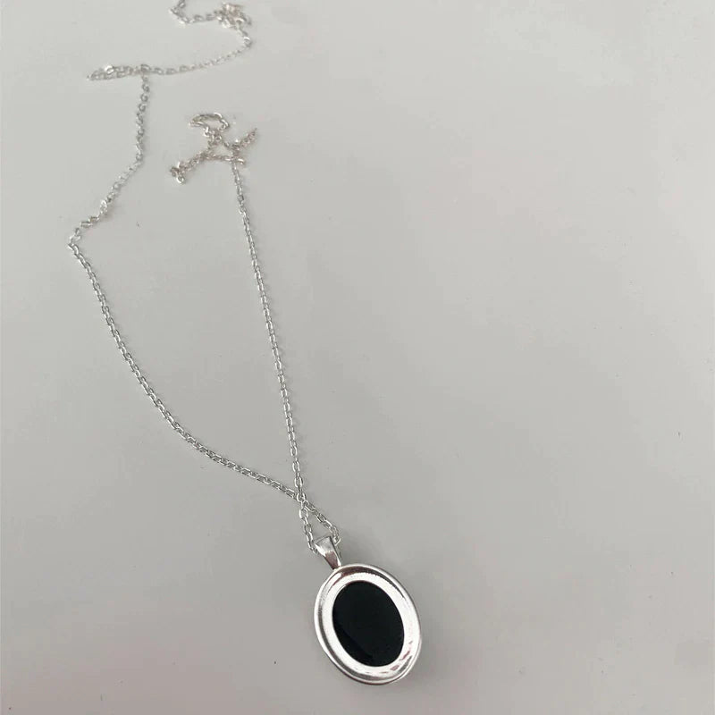 Silberne Halskette mit ovalem schwarzem Anhänger, eleganter Schmuck, Damenaccessoire.