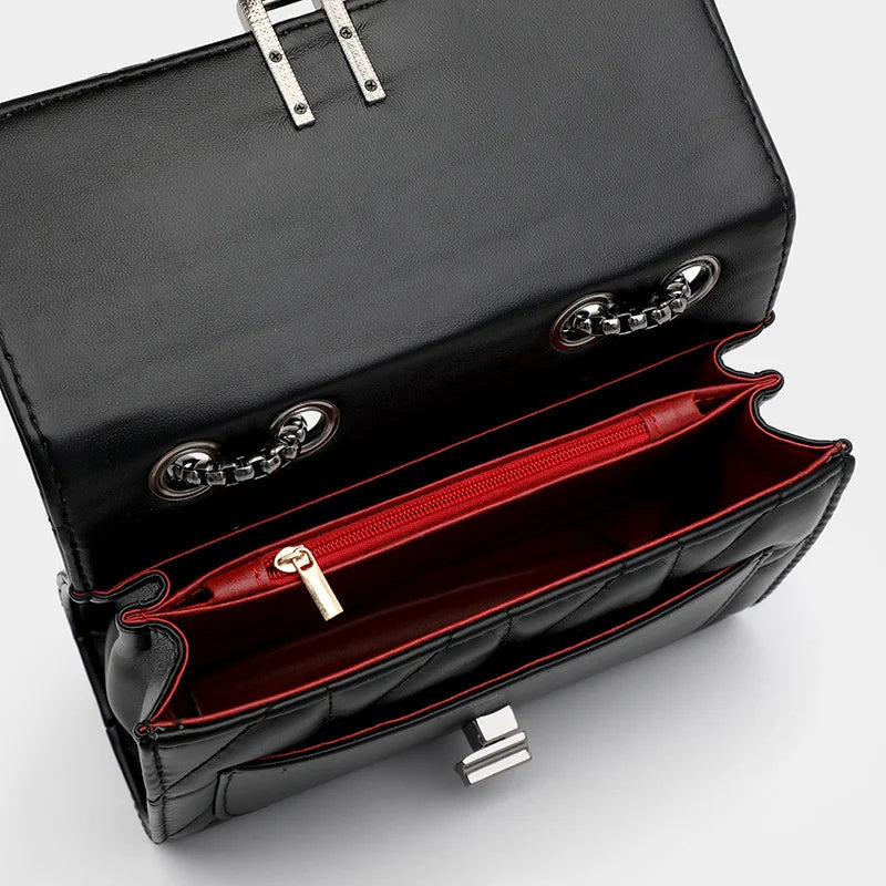 Schwarze Lederhandtasche mit rotem Innenfutter, Kettenriemen und Reißverschlussfach.