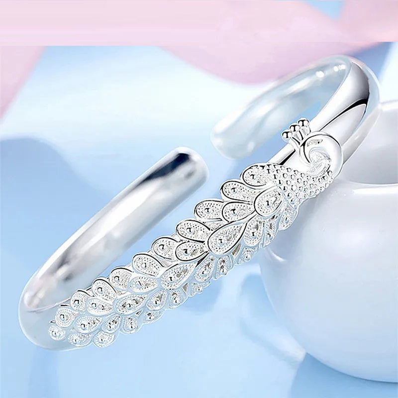Silbernes Pfauenarmband, elegantes Design, Schmuck für Damen, modisches Accessoire.