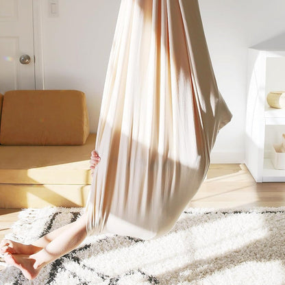 Beige Hängesessel im Wohnzimmer, gemütlich, modernes Design, ideal für Entspannung und Dekoration.