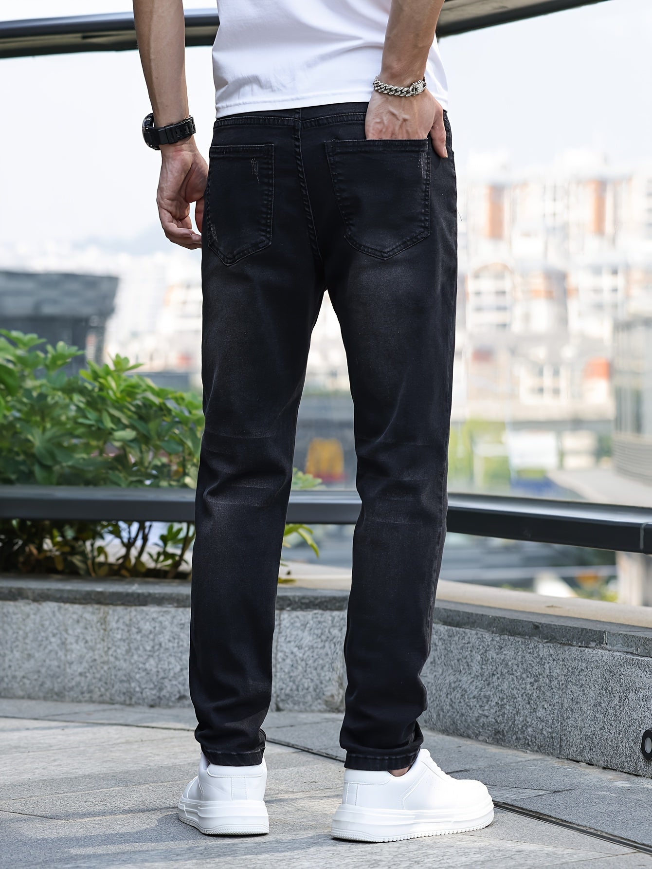 Mann in schwarzer Jeans und weißen Sneakers, Rückansicht, urbaner Hintergrund.
