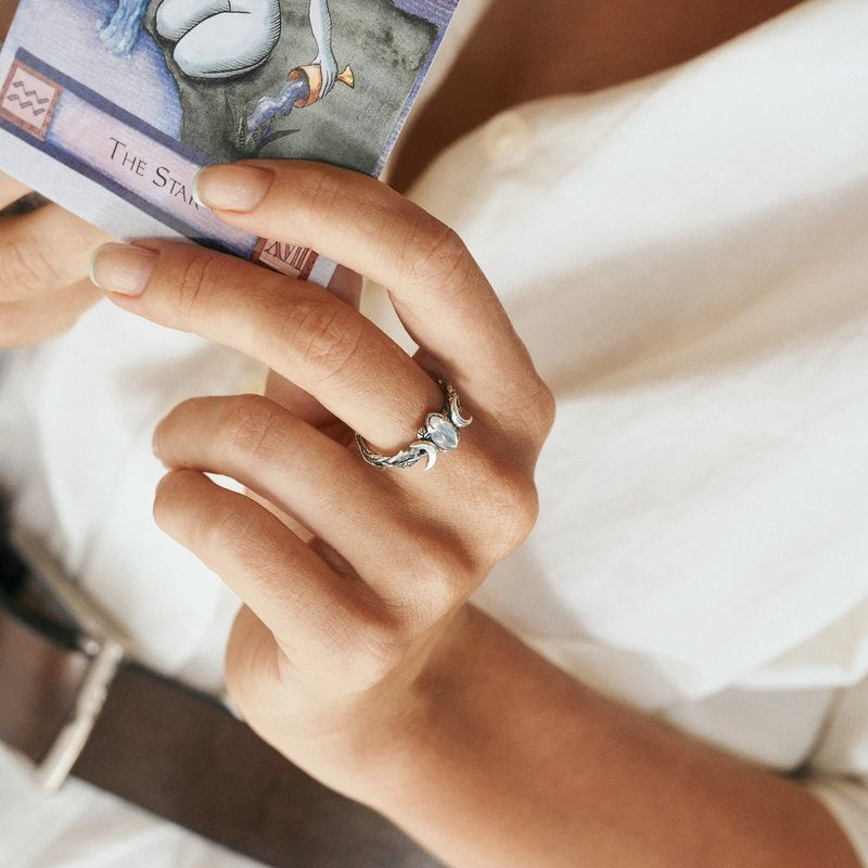 Frau mit Tarotkarte und silbernem Ring, weißes Hemd, Nahaufnahme, spirituelle Schmuckfotografie.