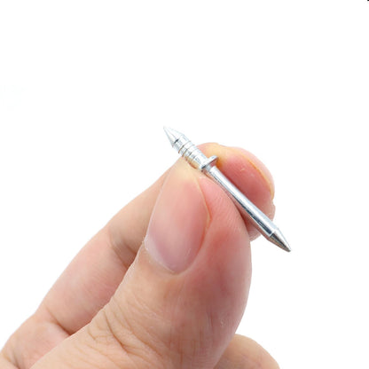En dubbelspetsad metallspik hålls mellan tumme och pekfinger, nära nog för att visa skaftet, kragen och de räfflade spetsarna. 4