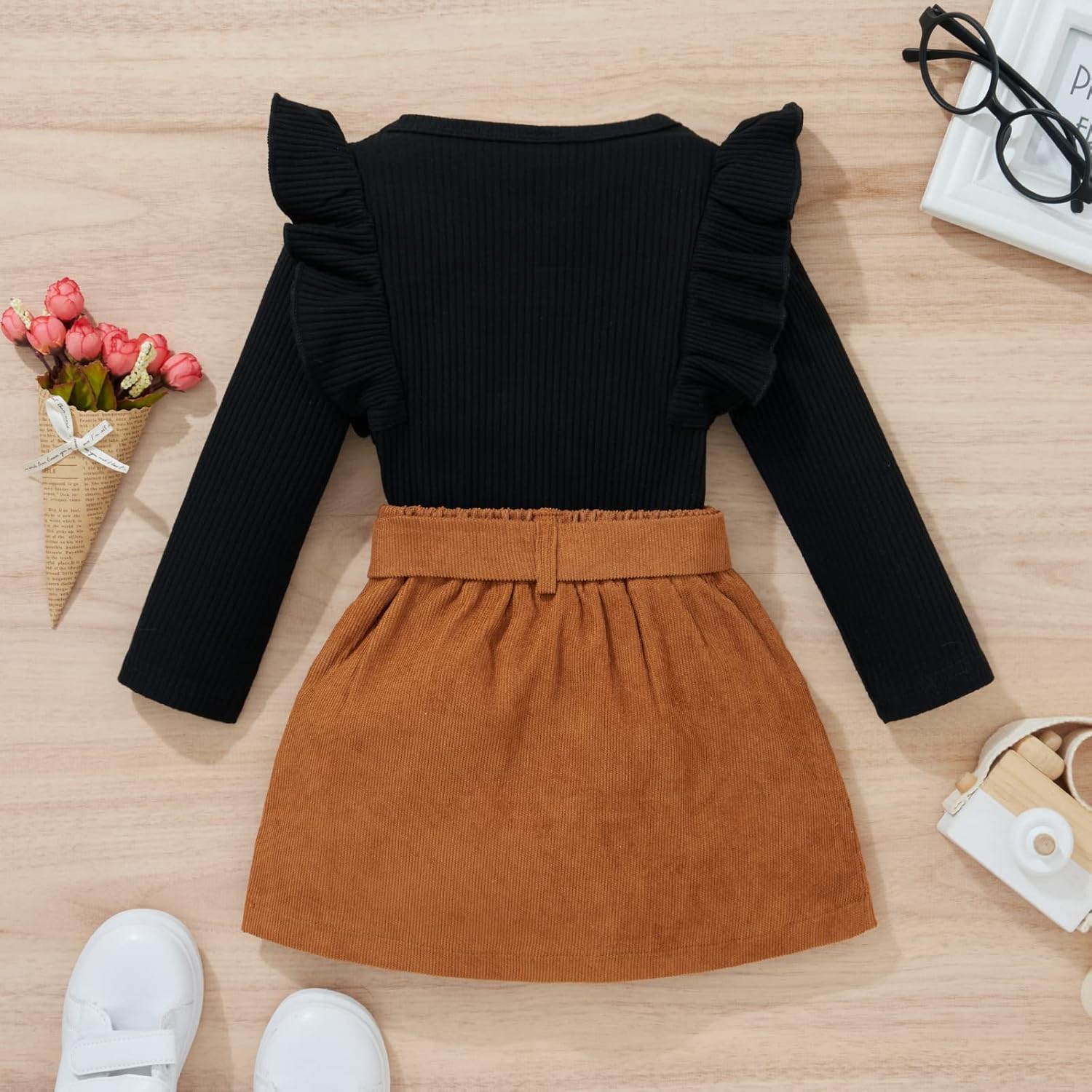 Schwarzes Langarm-Kleid mit Rüschen, brauner Rock, Kinderkleidung, Herbstmode, flach gelegt.