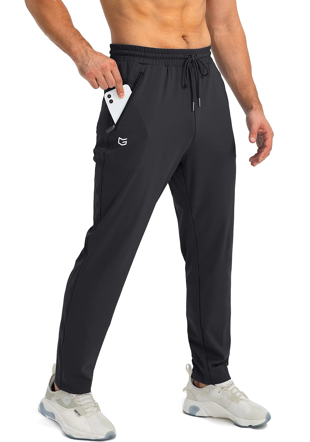 Mann in schwarzen Jogginghosen mit Smartphone in der Tasche, Sportbekleidung, Fitnessmode.