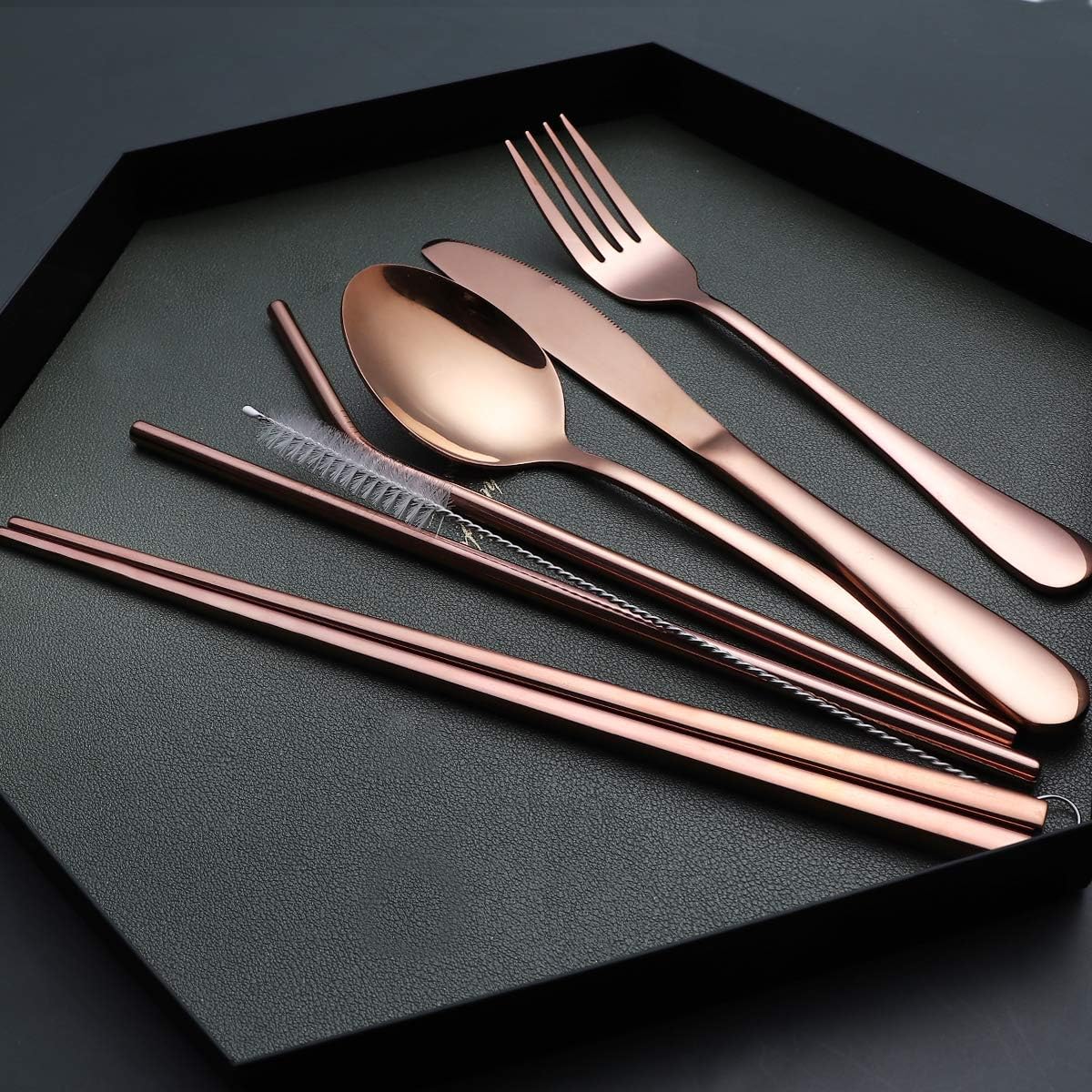 Rosenfarbenes Edelstahl-Besteckset mit Strohhalmen und Reinigungsbürste auf schwarzem Tablett.