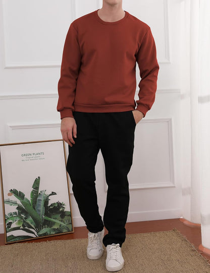 Mann in rotem Sweatshirt und schwarzer Hose, weiße Sneaker, modernes Wohnzimmer, Pflanzenposter.