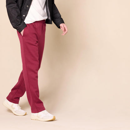 Mann in roten Jogginghosen, weißem T-Shirt und Sneakers auf beigem Hintergrund.
