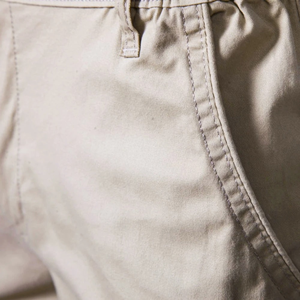 Närbild på en beige shortsficka med kantsöm och ett skärmlinningsöga vid midjan. 3