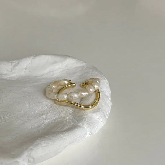 Goldener Ohrring mit Perlen, elegantes Schmuckdesign, luxuriöses Accessoire, minimalistisch.