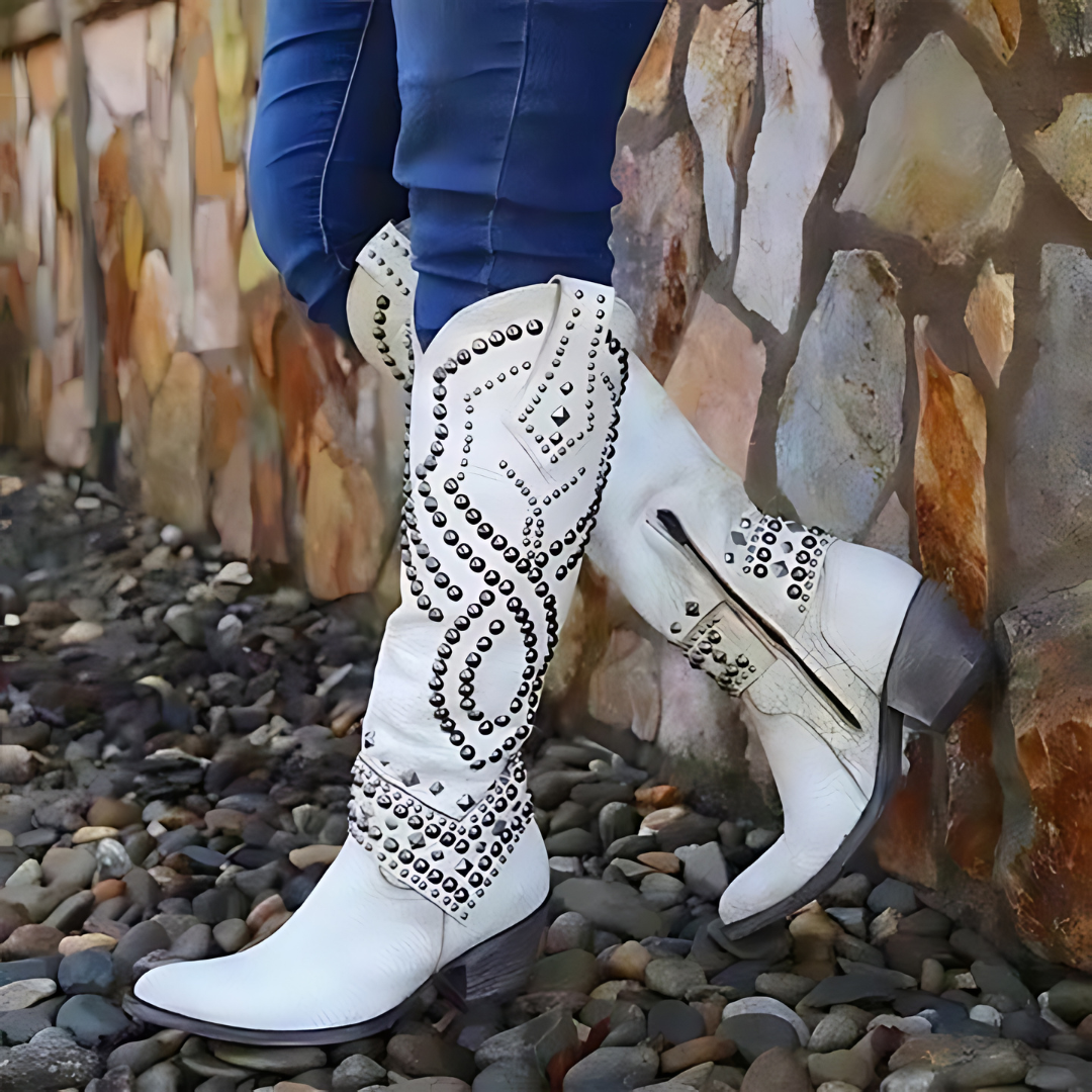 Weiße Cowboystiefel mit Nieten, Damenmode, Leder, Steinwand, modische Stiefel, Outdoor.