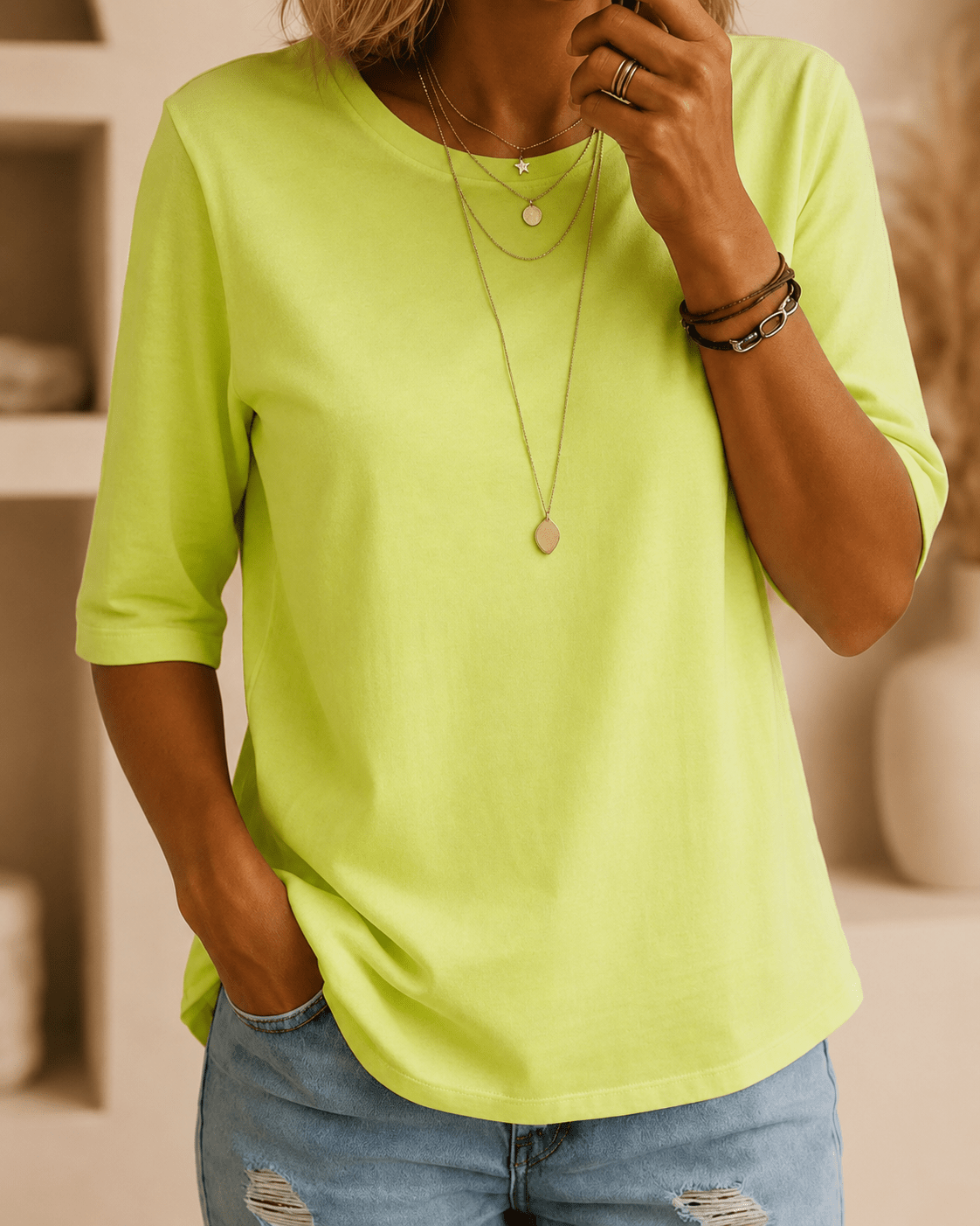 Modell bär den neongröna t-shirten med rund hals och halvlånga ärmar, med lösa guldhalsband, armband och ljusa slitna jeans. 1