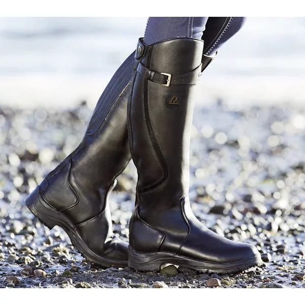 Schwarze Reitstiefel aus Leder am Strand, robust und wasserdicht, ideal für Outdoor-Aktivitäten.