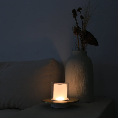 Moderne Tischlampe mit warmem Licht neben weißer Vase auf Sofa, minimalistische Wohnkultur.