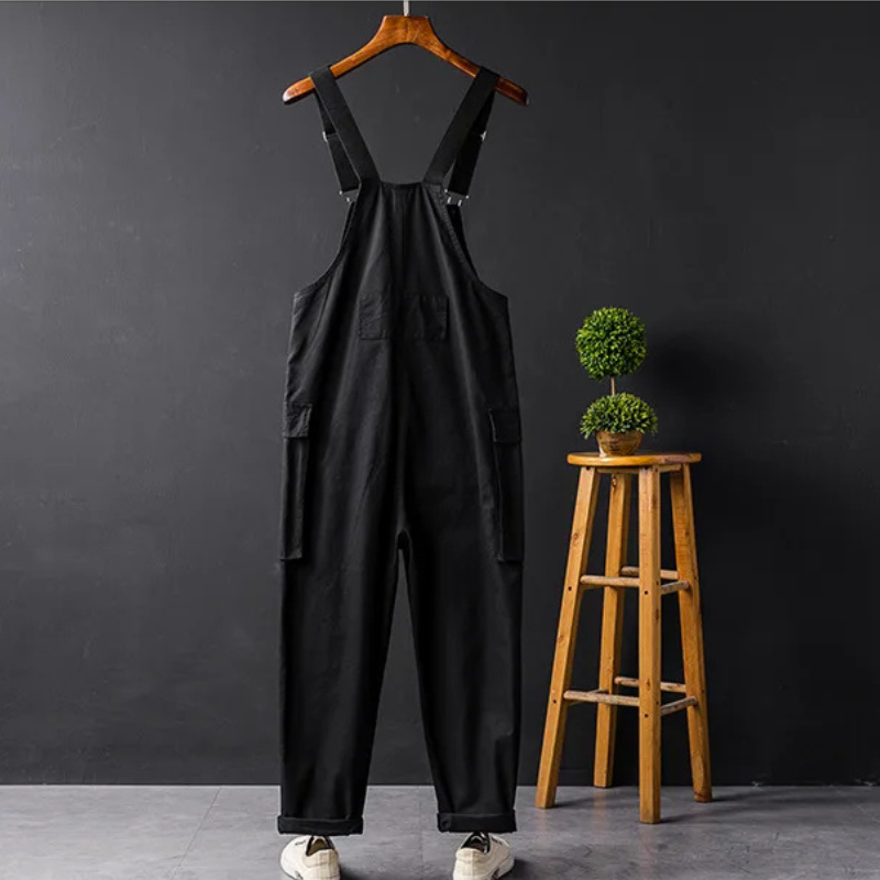 Schwarzer Unisex-Overall aus Baumwolle, lässig, mit Taschen, auf Holzkleiderbügel.