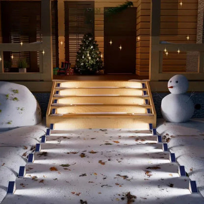 Beleuchtete Außentreppe mit Schneemann und Weihnachtsbaum, winterliche Dekoration, Nachtansicht.
