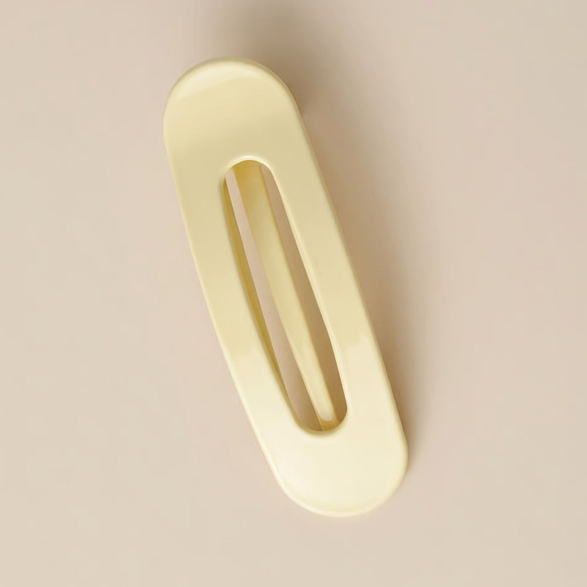 Blank blekgul hårklämma med avlång öppning liggande på beige bakgrund 6