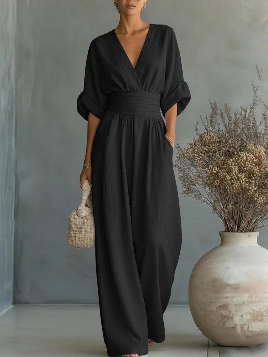 Svart jumpsuit med V-ringning, rynkad midjekant och vida byxben, buren av en kvinna med flätad väska och kruka. 5