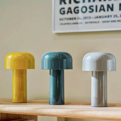 Drei bunte, pilzförmige Tischlampen auf Holzregal, modern, gelb, blau, weiß.