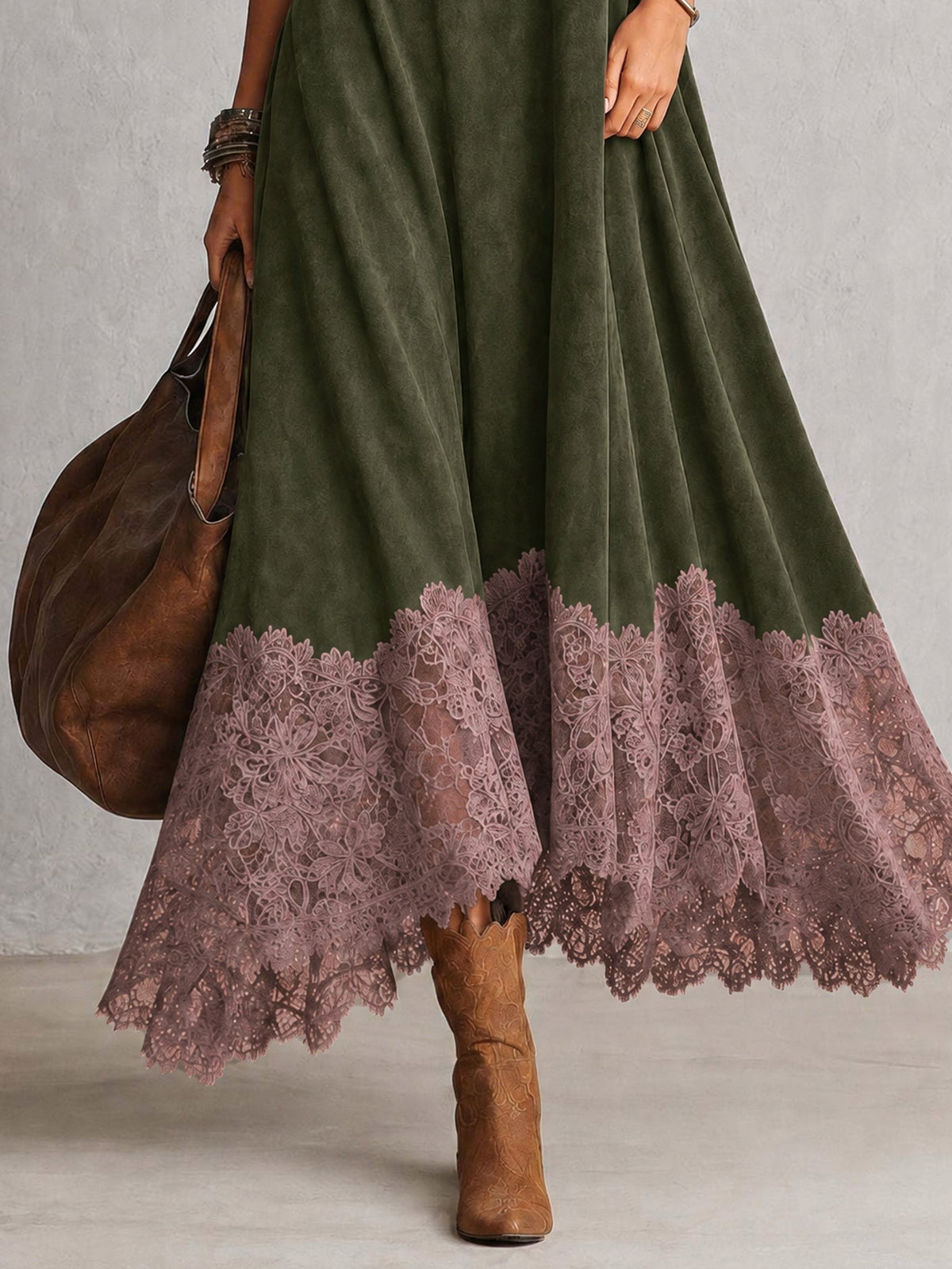 Närbild på den olivgröna klänningens rosa spetskant, med brun väska och boots 16