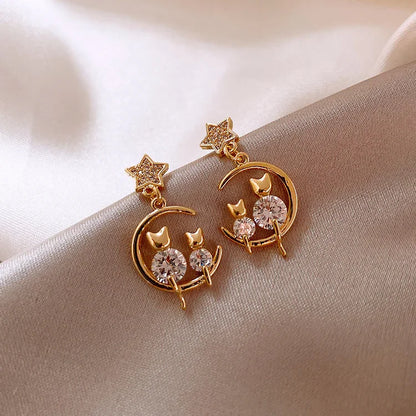 Goldene Ohrringe mit Stern- und Mondmotiv, Katzen-Design, funkelnde Kristalle, elegant, modisch.