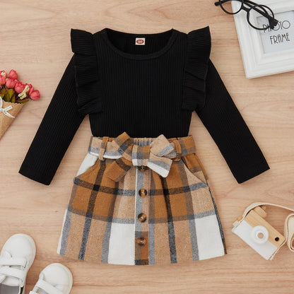 Schwarzes Kinderkleid mit Rüschenärmeln und kariertem Rock, Herbstmode für Mädchen.