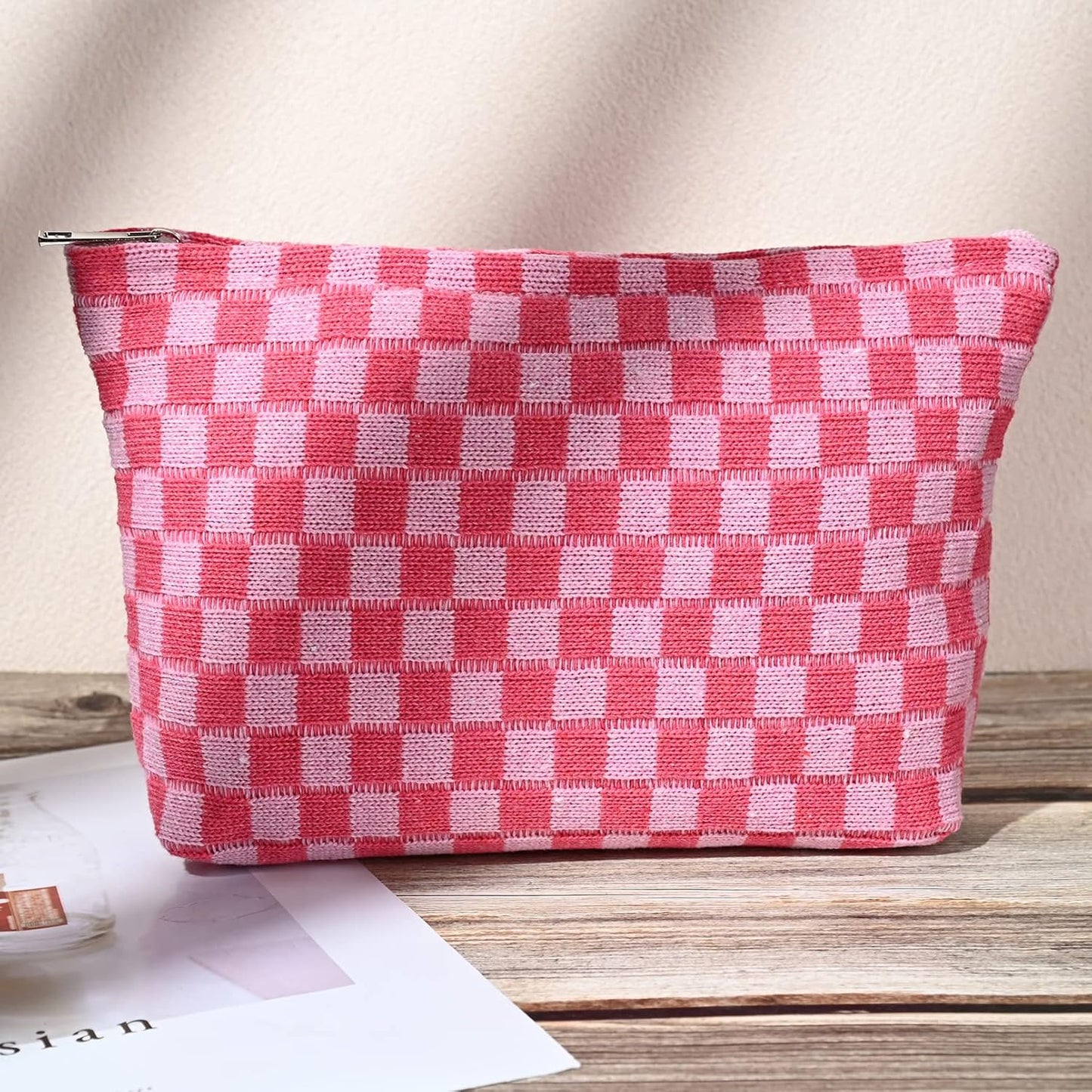 Rosa-weiß karierte Kosmetiktasche aus Stoff mit Reißverschluss auf Holztisch.
