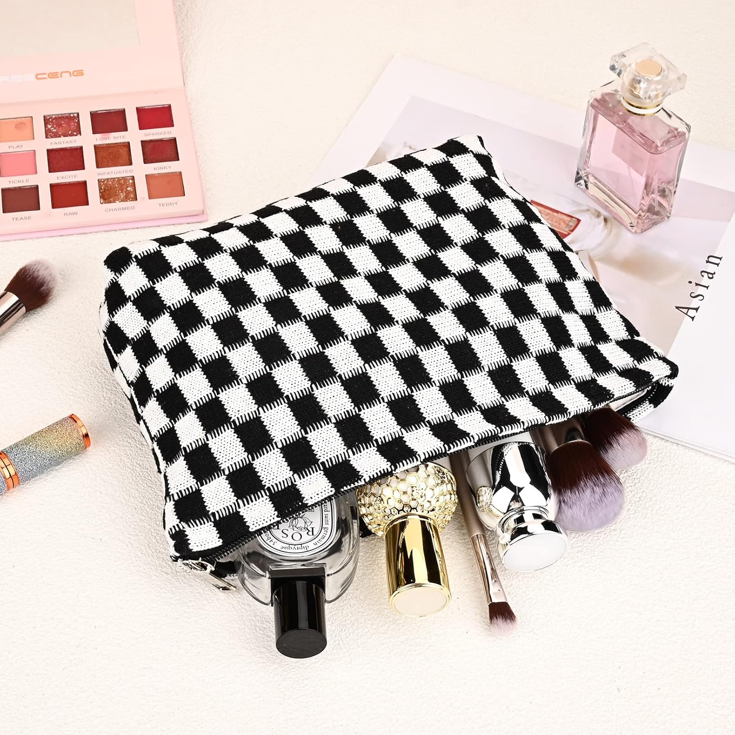 Schwarz-weiß karierte Kosmetiktasche mit Make-up-Produkten, Parfüm und Lidschatten-Palette.