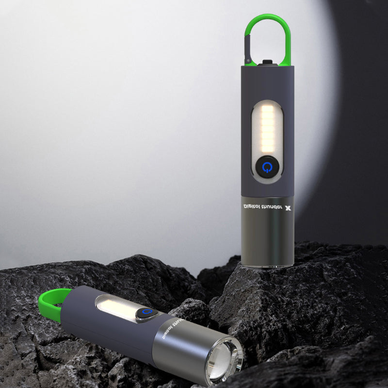 Zwei tragbare LED-Taschenlampen, schwarz mit grünem Griff, auf Felsen im Freien.