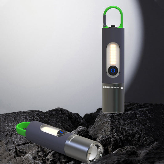 Zwei tragbare LED-Taschenlampen, schwarz mit grünem Griff, auf Felsen im Freien.