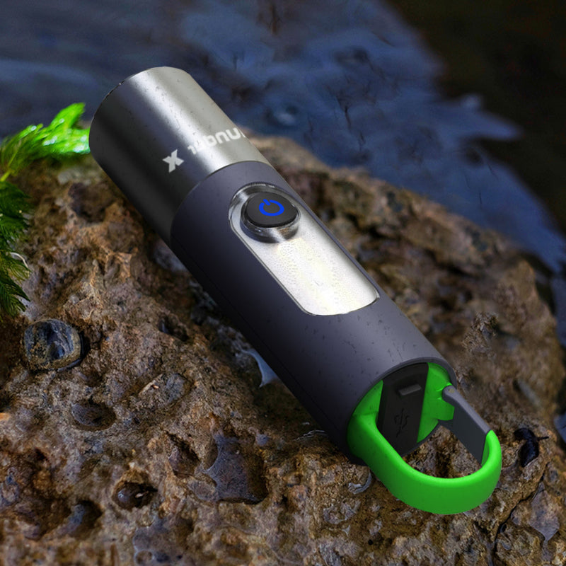 Schwarze tragbare Taschenlampe mit grünem Haken, wasserdicht, auf Felsen im Freien.