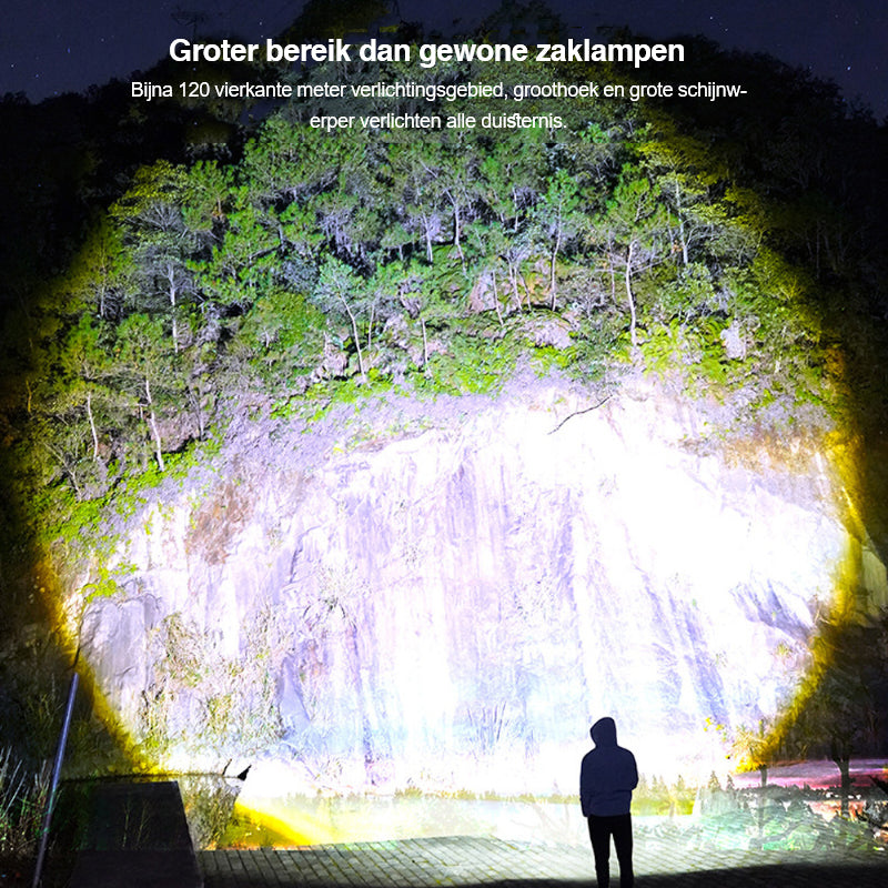 Person mit starker Taschenlampe beleuchtet große Felswand bei Nacht, Wald im Hintergrund.